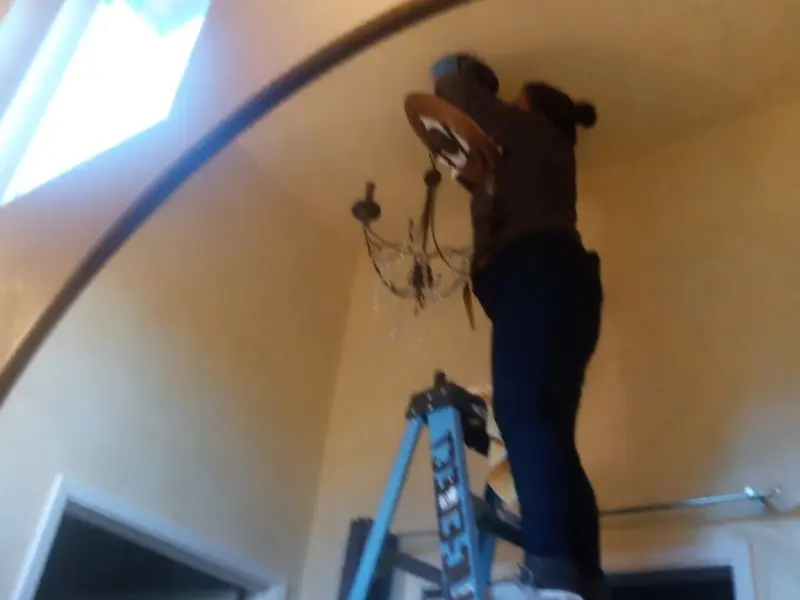 Electrician installing a chandelier in a Midland residence